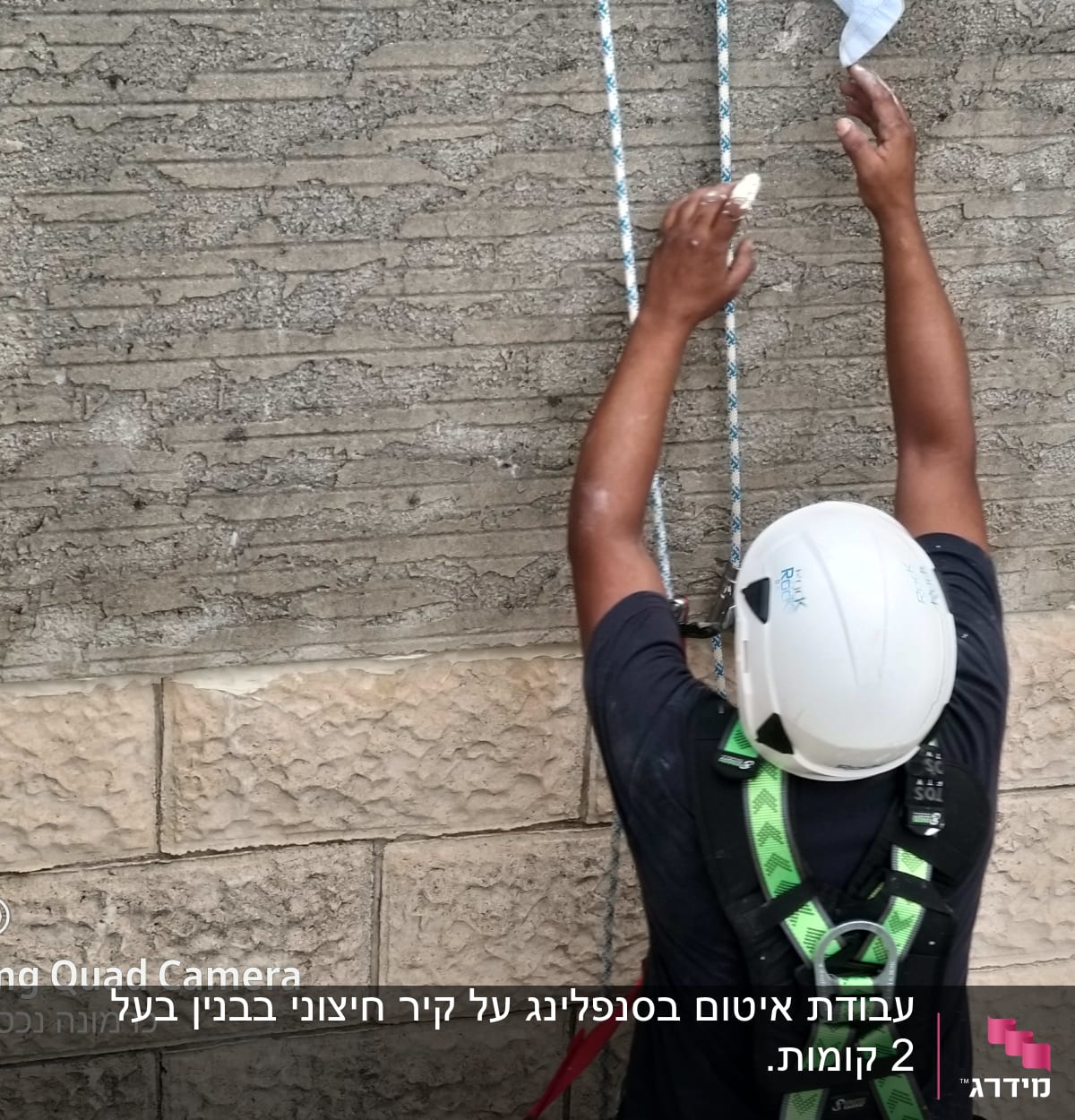 אדם עם קסדה וריתמה עובד על קיר עם חבלים